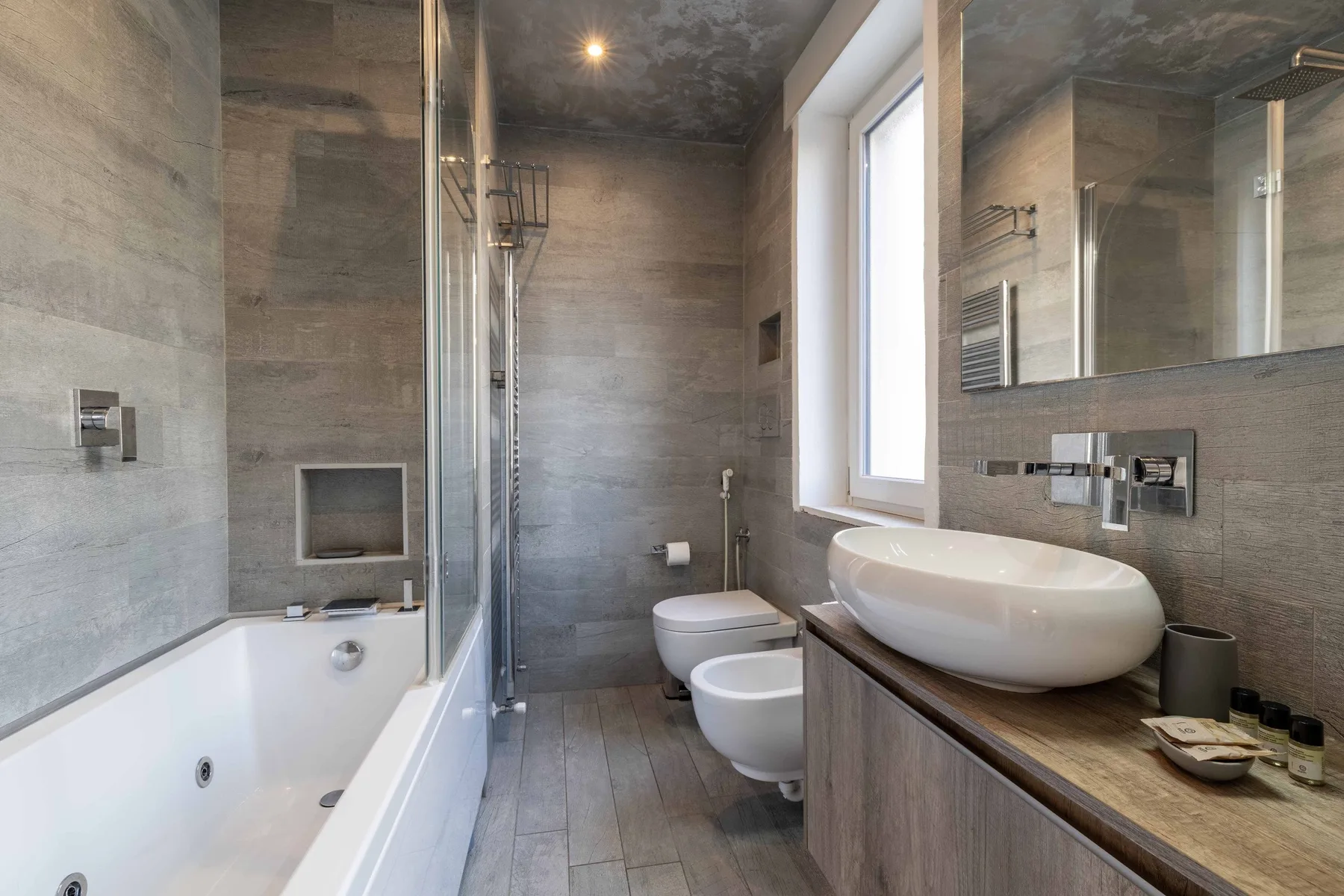 Un baño moderno con bañera, ducha de vidrio y lavabo sobre encimera.