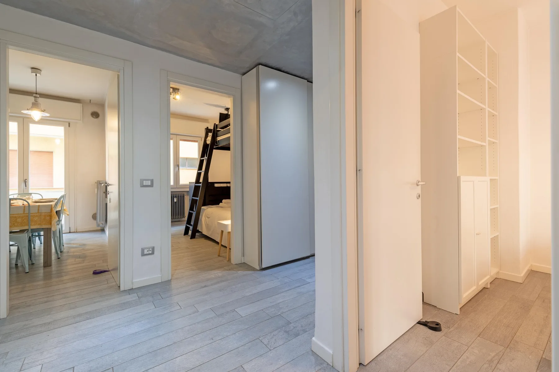 Un pasillo interior luminoso con puertas abiertas que dan a habitaciones amuebladas.