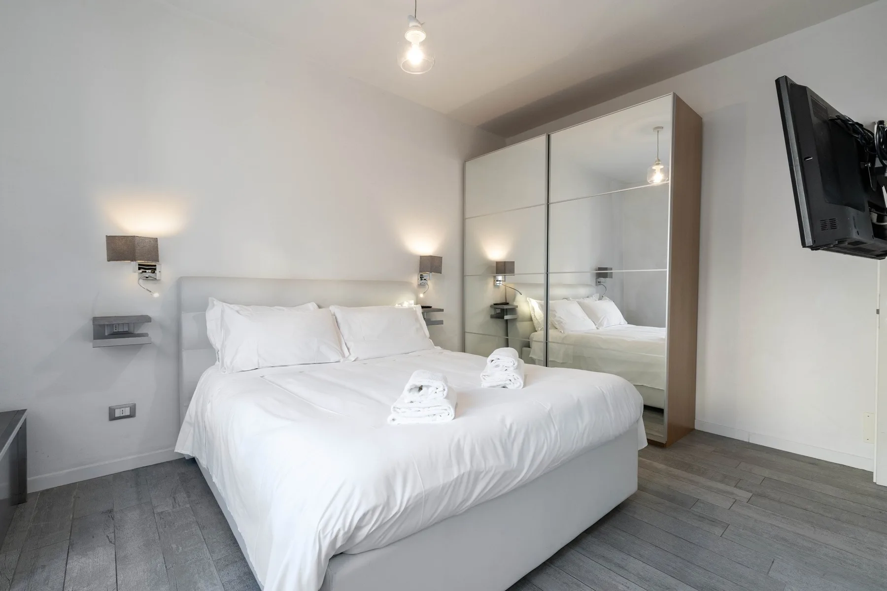Un dormitorio luminoso con una cama bien tendida y un armario con espejo.