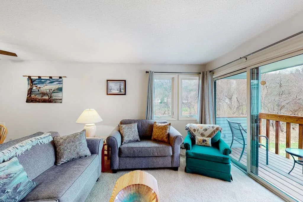 A living room with seating beside large windows and a sliding glass door.