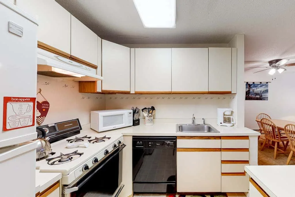 A bright kitchen with white cabinets, a stove, and a sink.