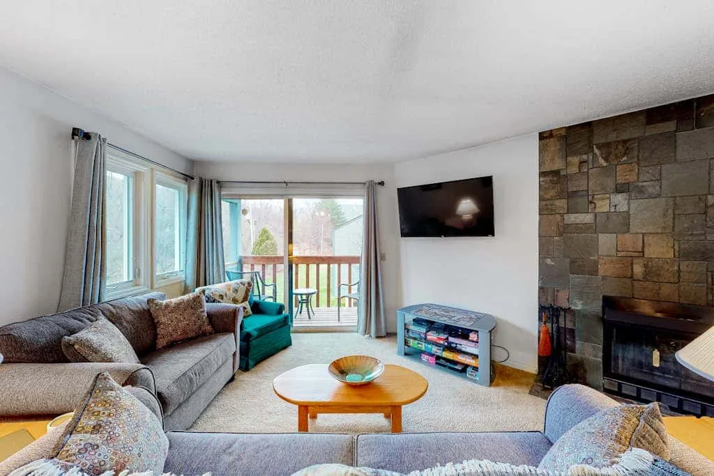 A living room with seating, a coffee table, and a stone fireplace.