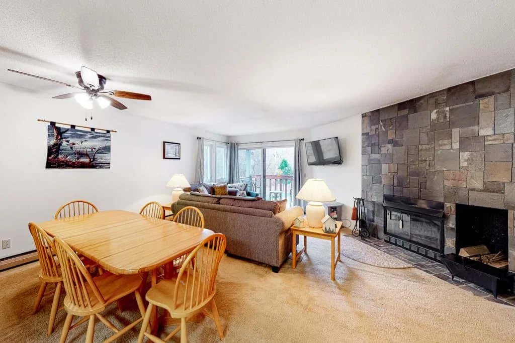 A living and dining room with a fireplace and seating.