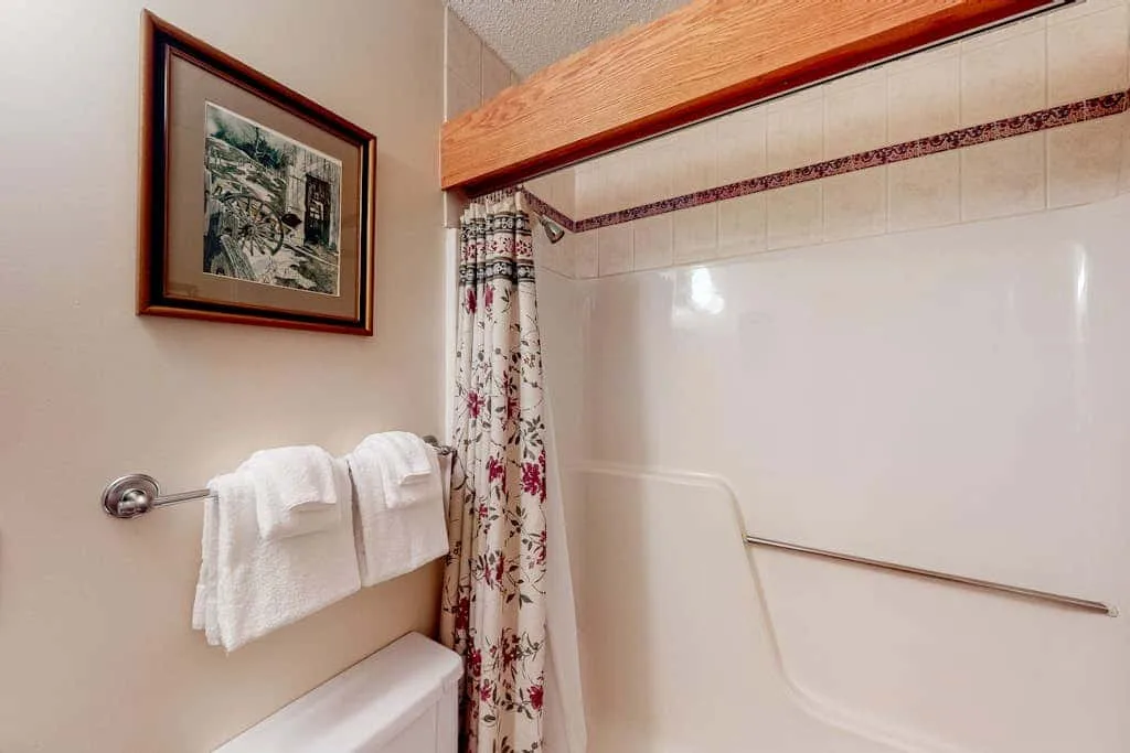A bathroom with a bathtub, shower curtain, and towels hanging on the wall.