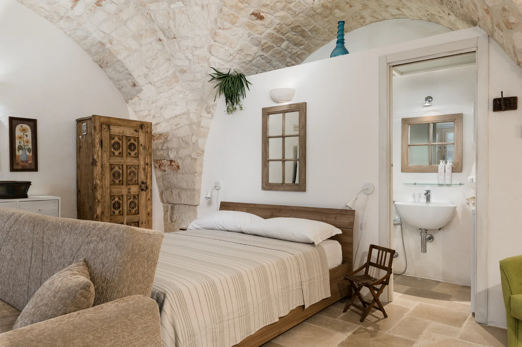 A bedroom with a bed and an adjoining bathroom visible through an open doorway.