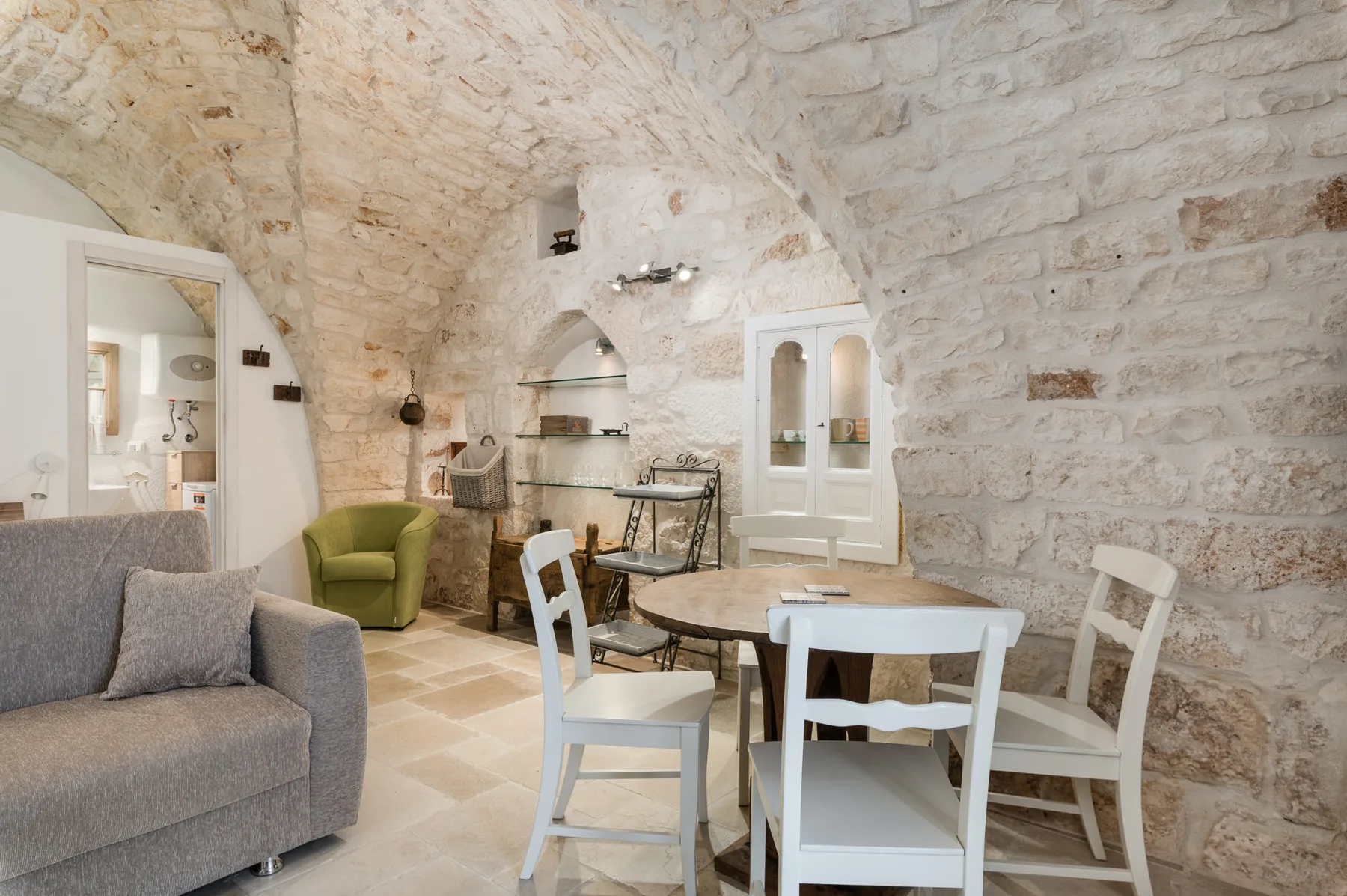 A stone dining area with a table and chairs beside a gray sofa.