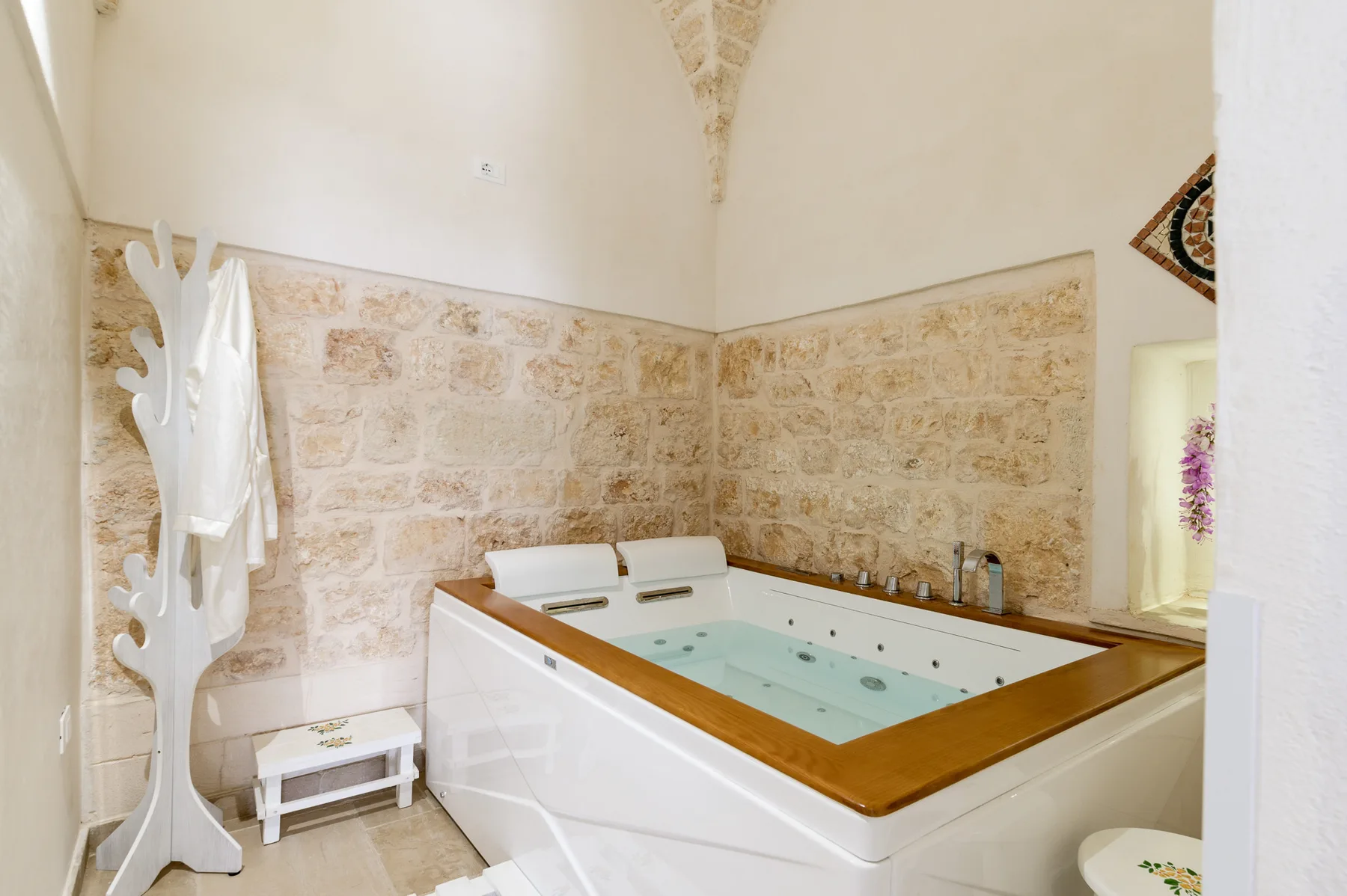 A large indoor whirlpool tub sits against pale stone walls.