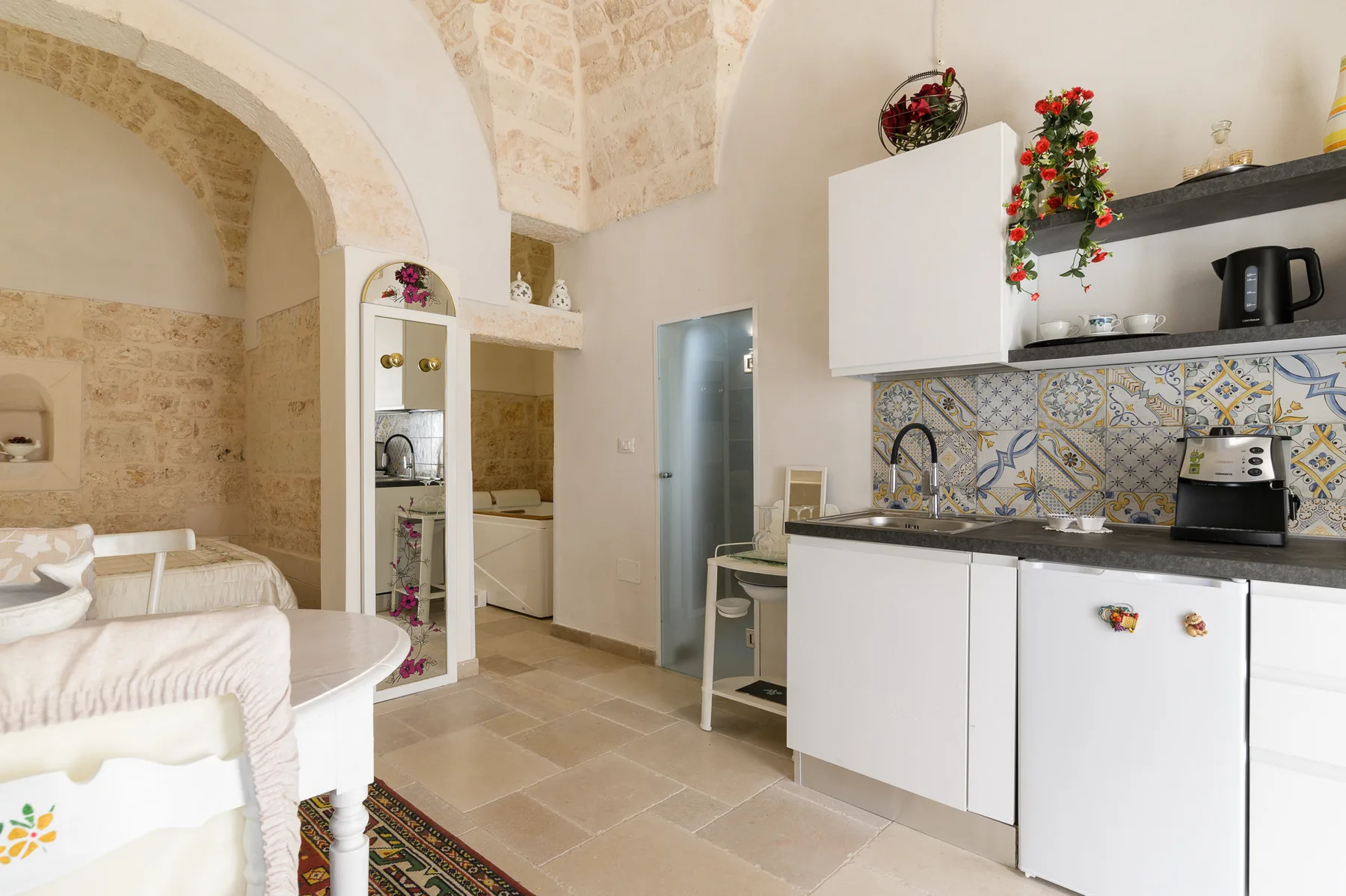 A compact kitchen with white cabinets, a tiled backsplash, and a small dining area.