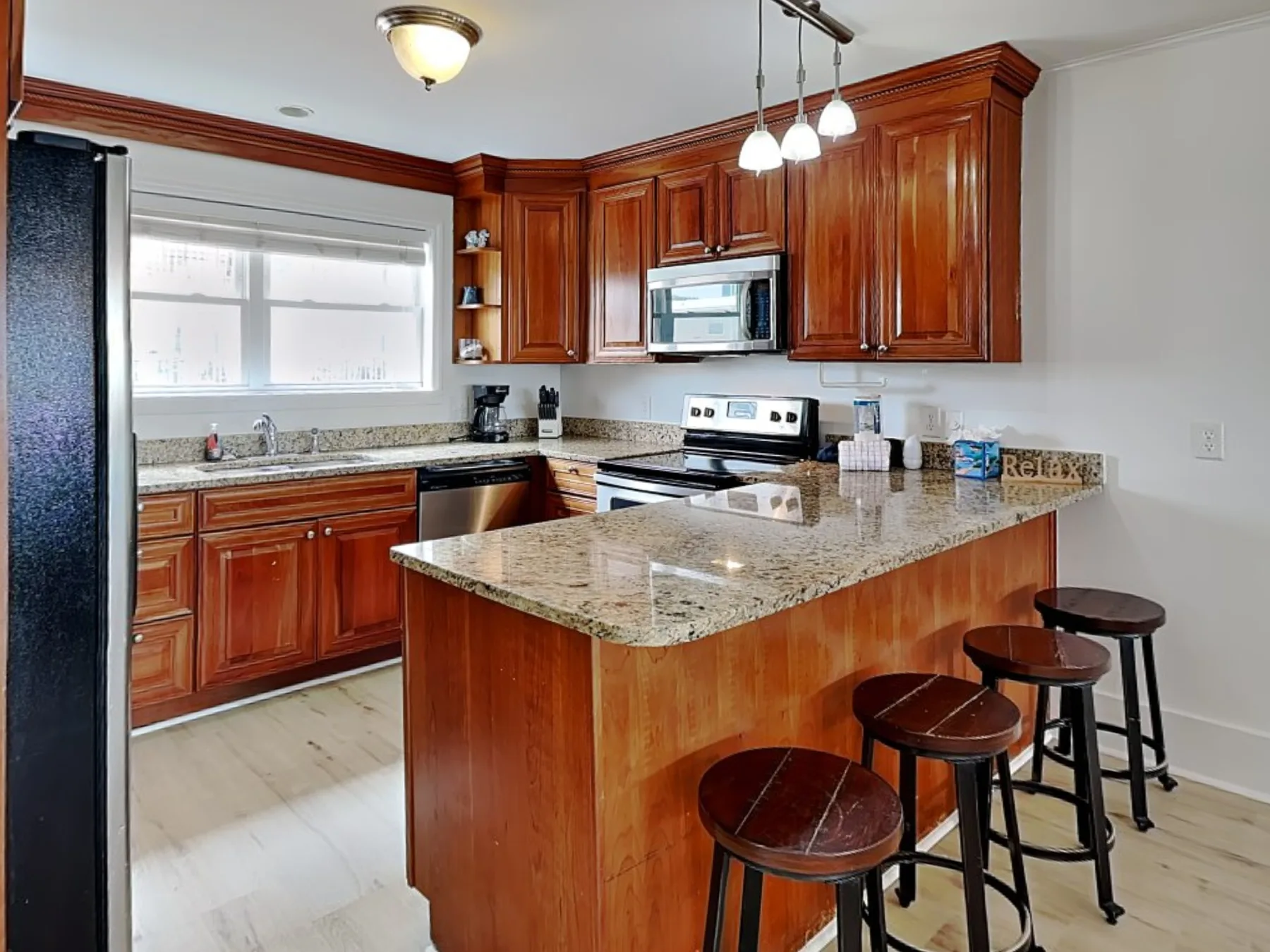Una cocina con gabinetes de madera y una isla de granito con asientos.