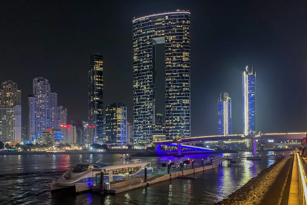 El perfil urbano junto al río se refleja de noche junto a un puente iluminado.