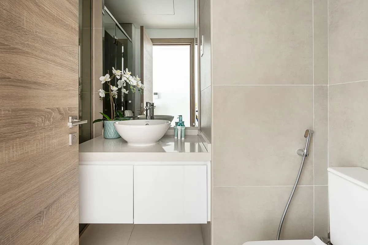 Un baño moderno con lavabo sobre encimera, espejo y ducha de mano.