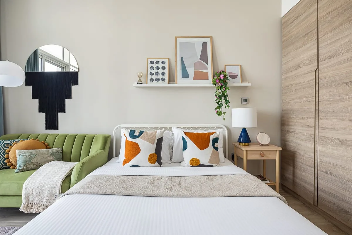 Un dormitorio con una cama bien tendida y un sofá verde al lado.