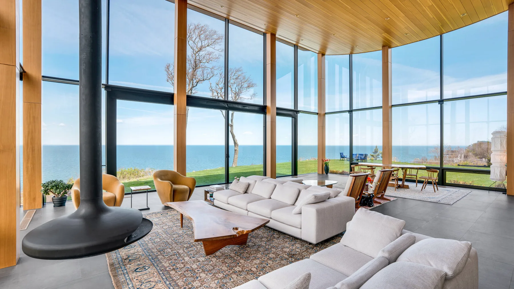 A spacious living room with floor-to-ceiling windows and seating overlooking the sea.