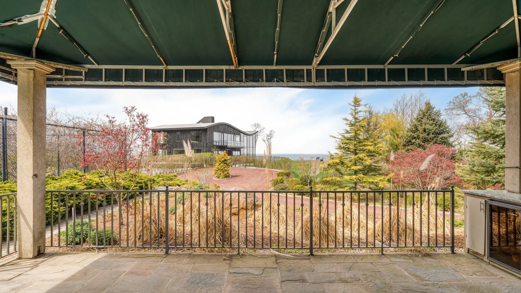 A covered terrace overlooks landscaped grounds and trees.