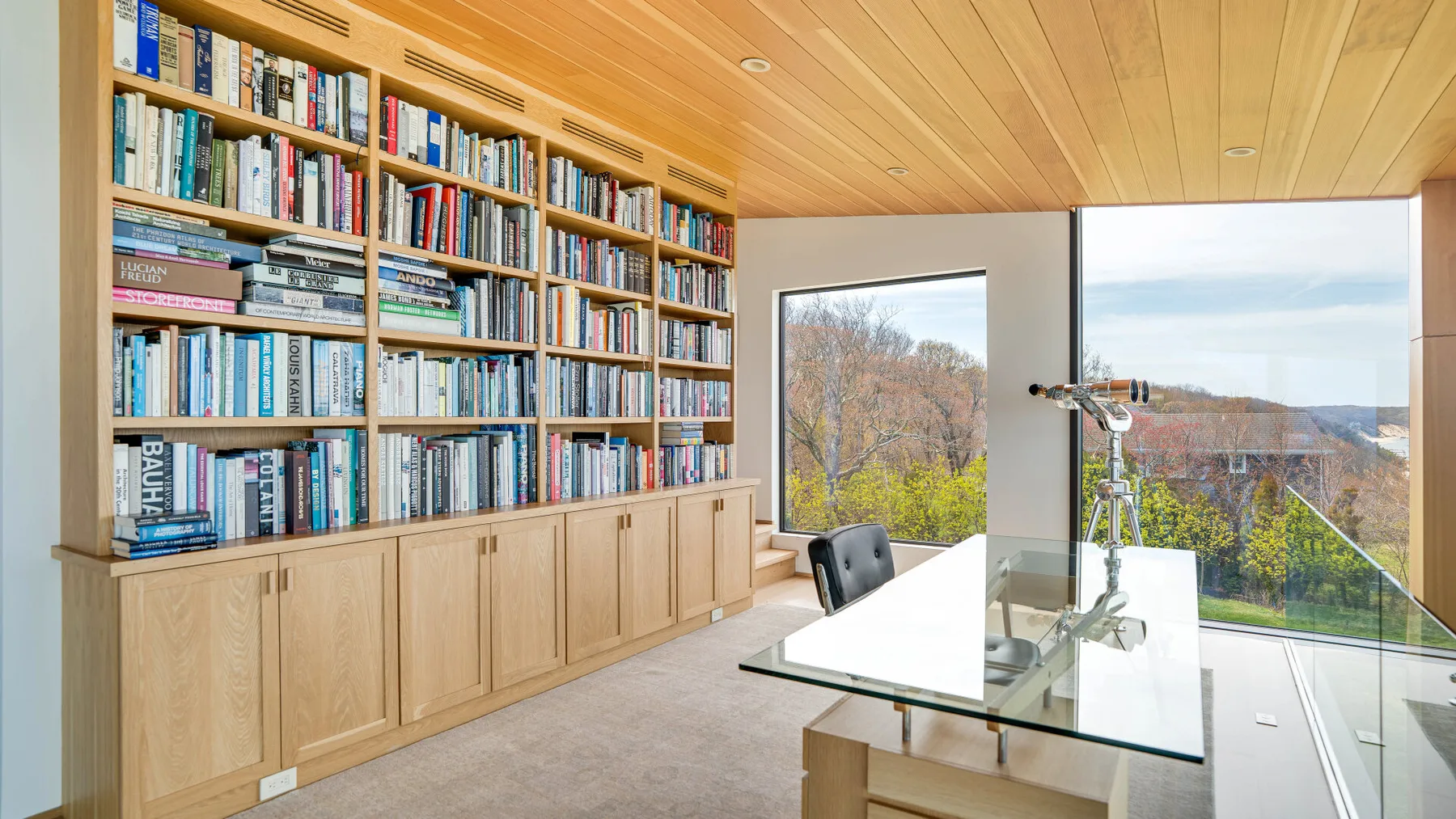 A bright home office with a wall of bookshelves and a glass desk.