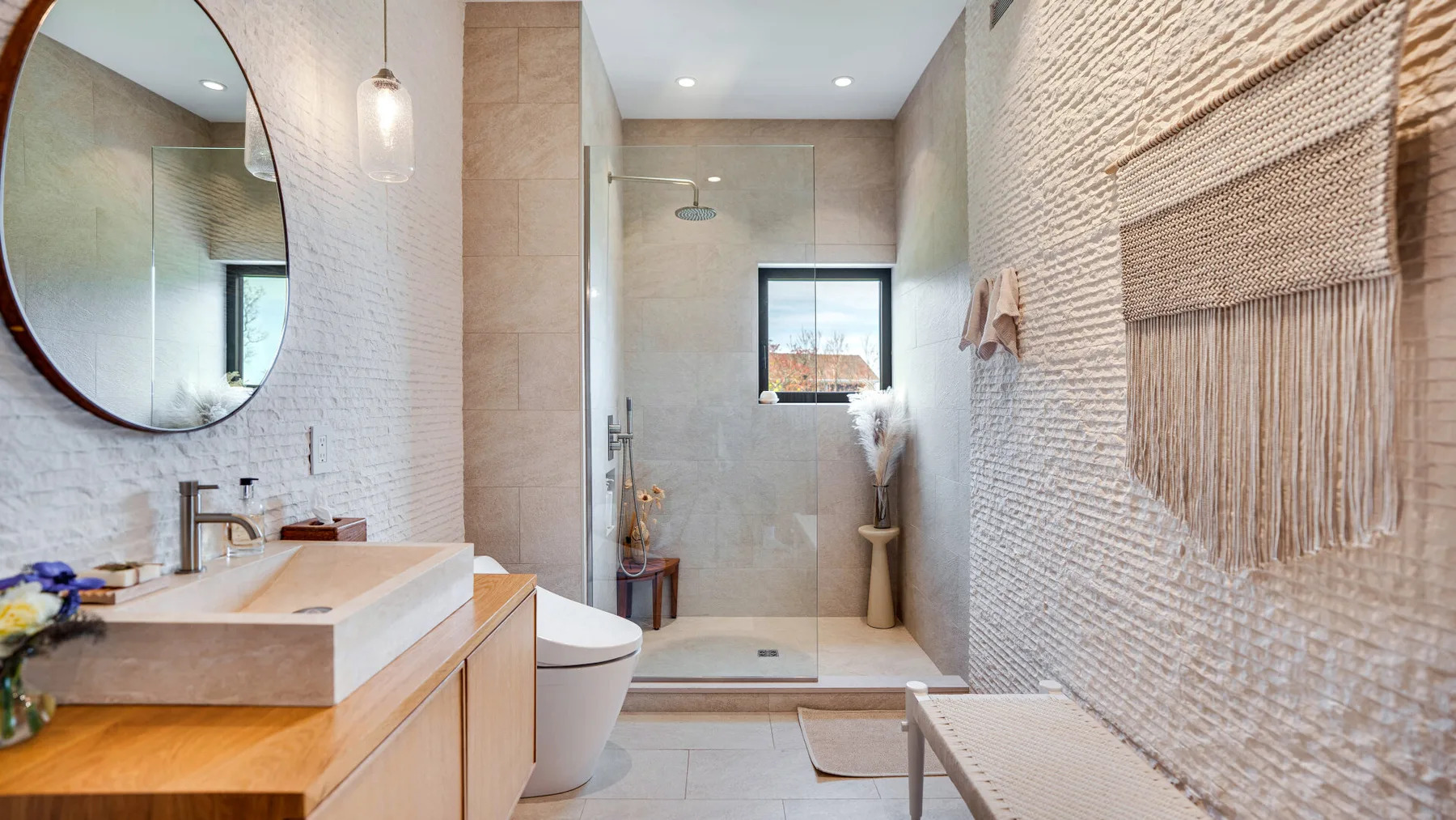 A bright bathroom with a walk-in shower and a vanity beneath a round mirror.