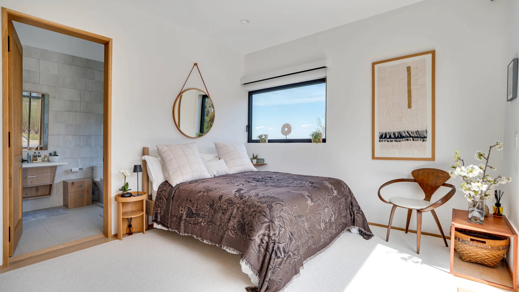A bedroom with a bed, a round mirror, and a framed wall print.