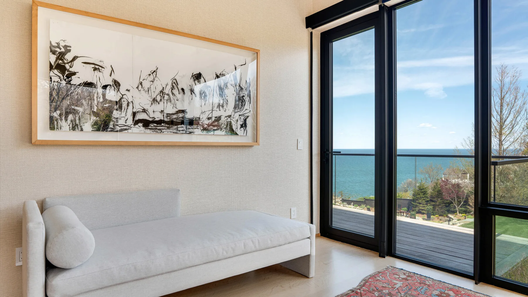 A bright sitting area with a light-colored sofa and large windows overlooking the water.