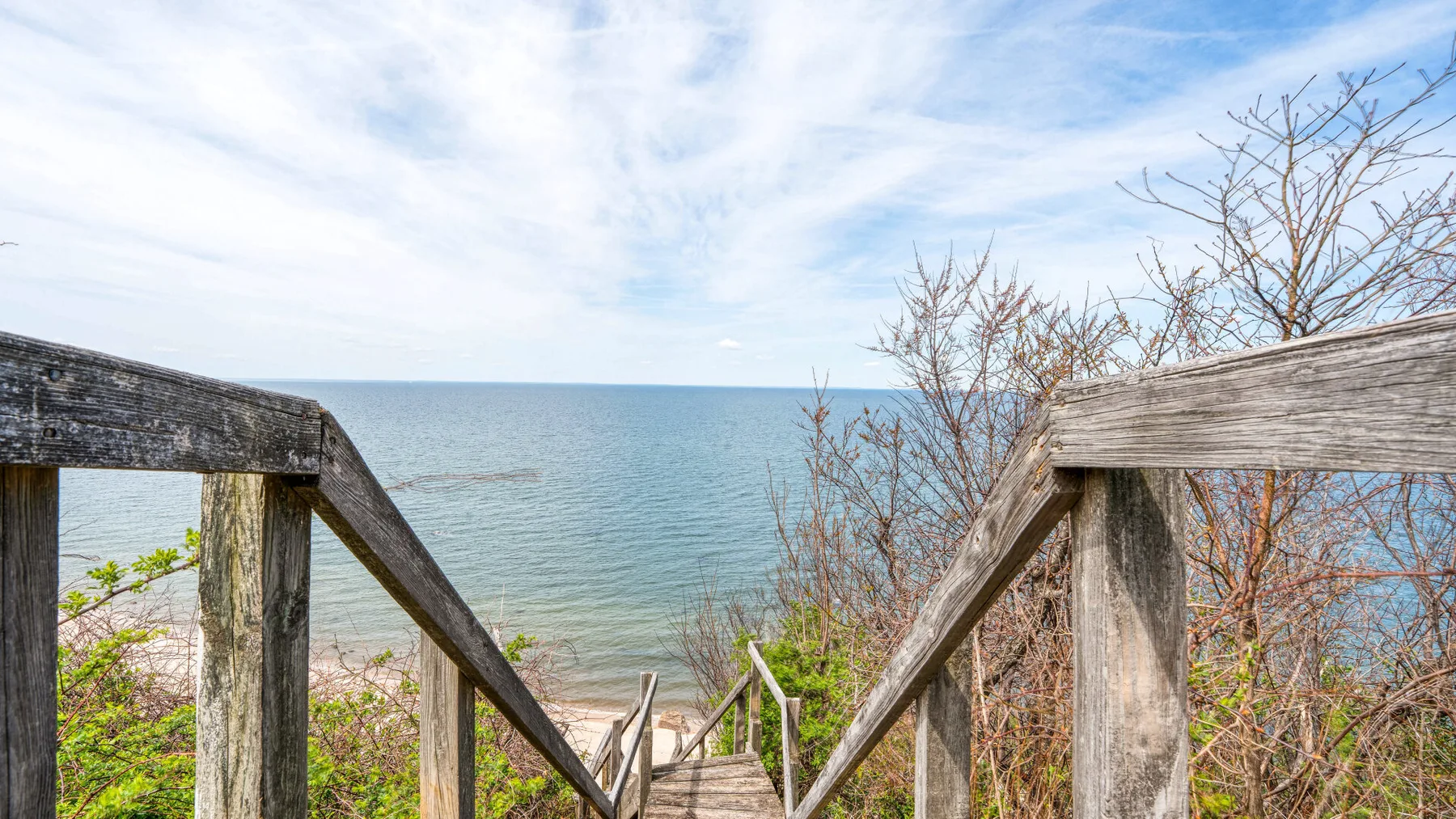 Wooden steps descend toward a beach with the ocean visible beyond.