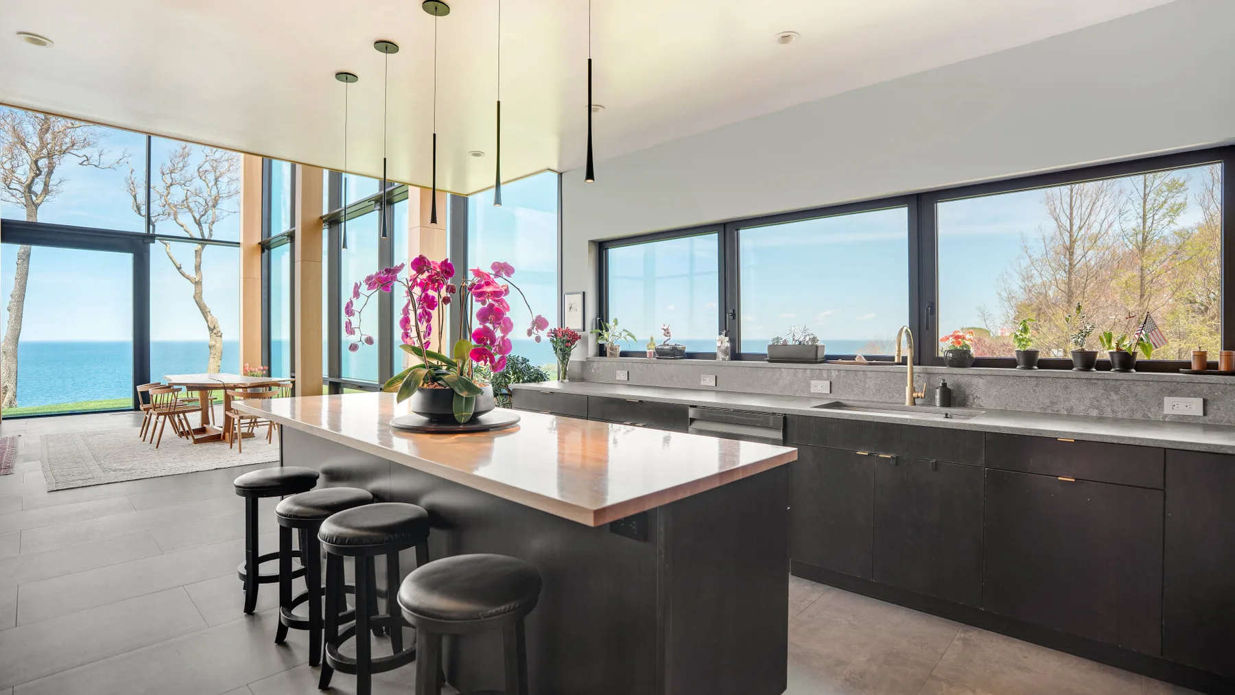 A modern kitchen with a central island and large windows overlooking the water.