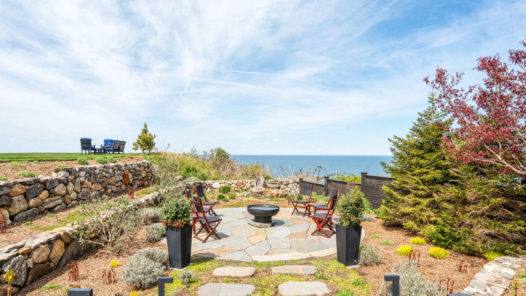 A stone patio with outdoor seating overlooks the water.