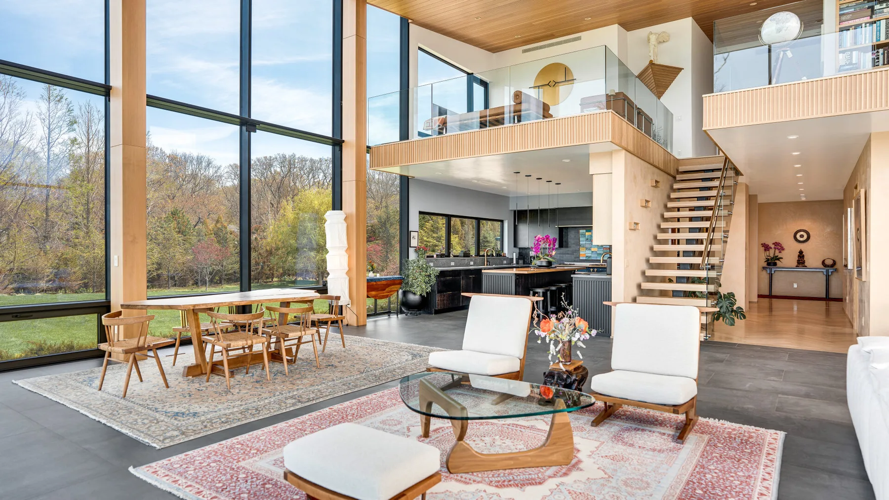 A bright open-plan living and dining area with tall windows and a staircase.
