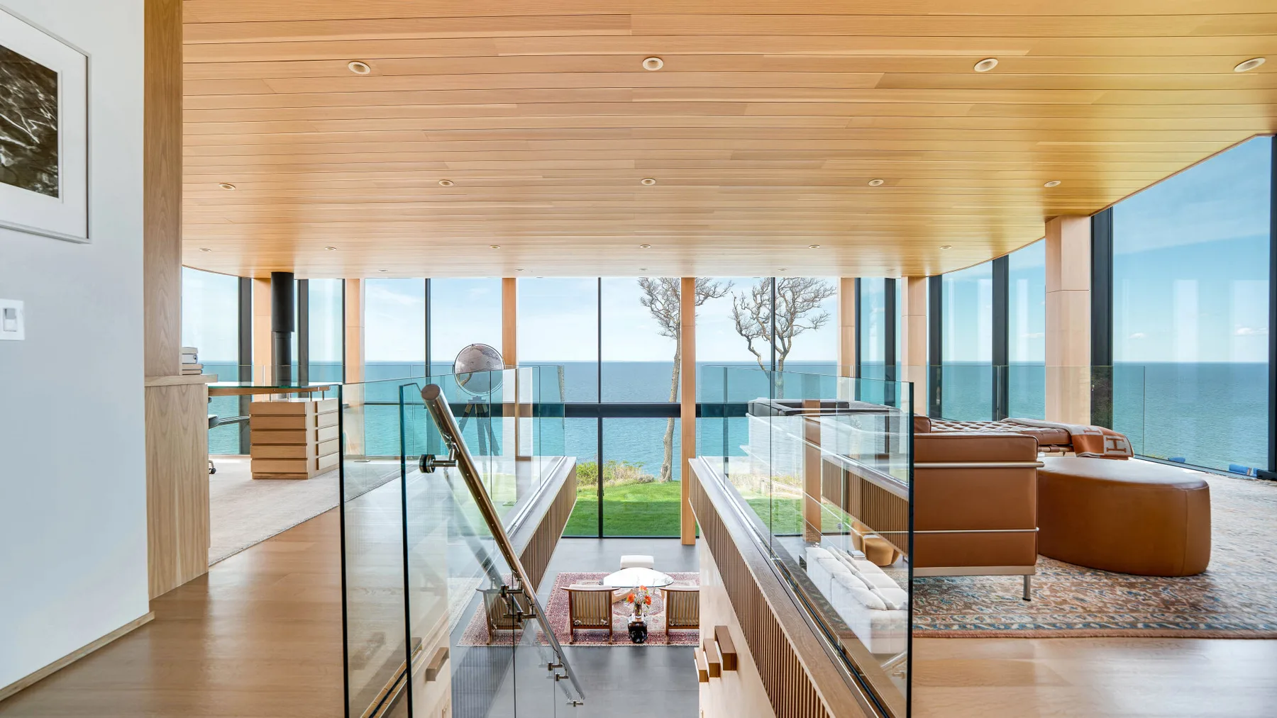 A bright modern living area overlooks the ocean through large windows.