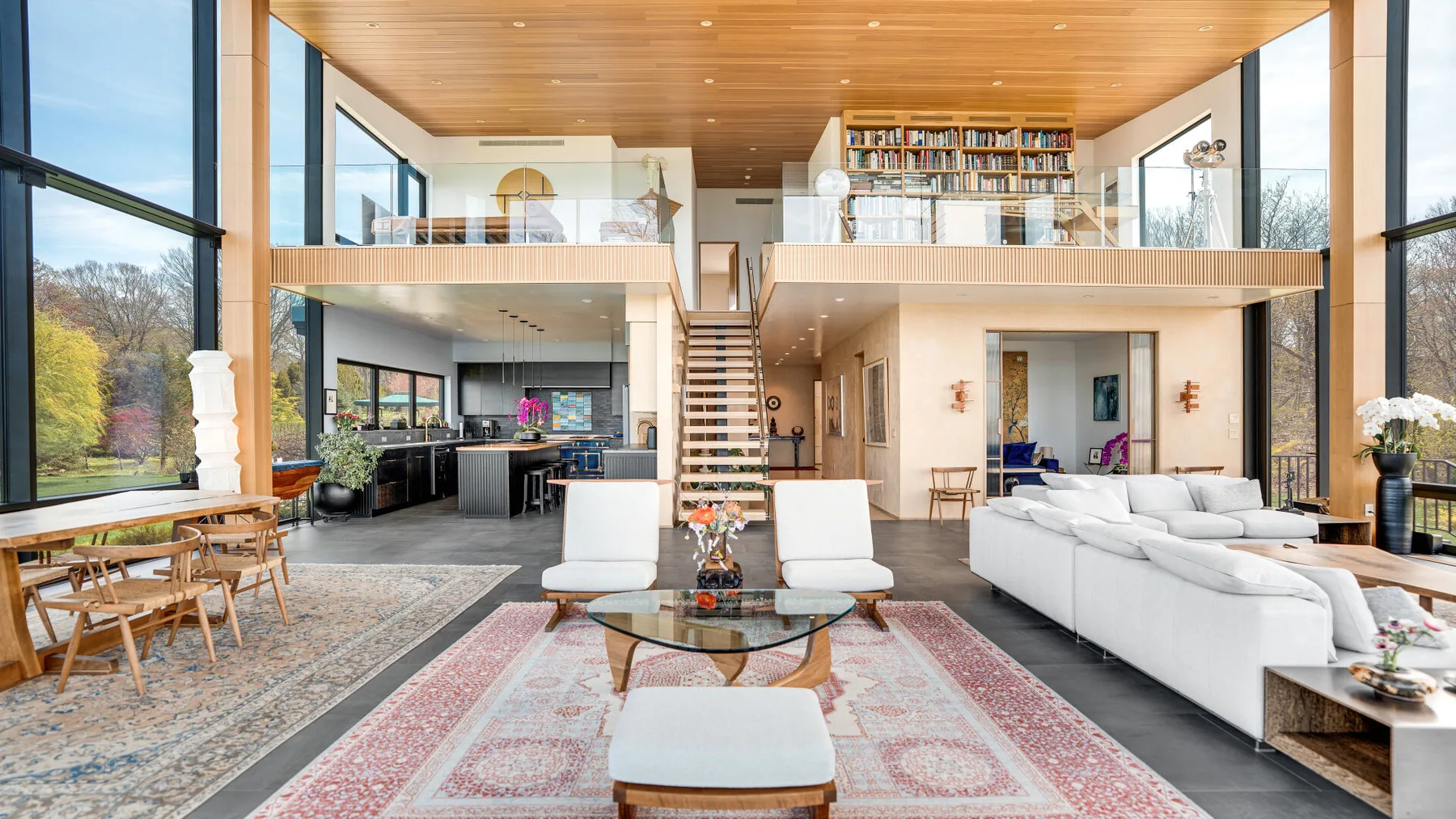 A bright open-plan living room with a dining area and a staircase to the upper level.