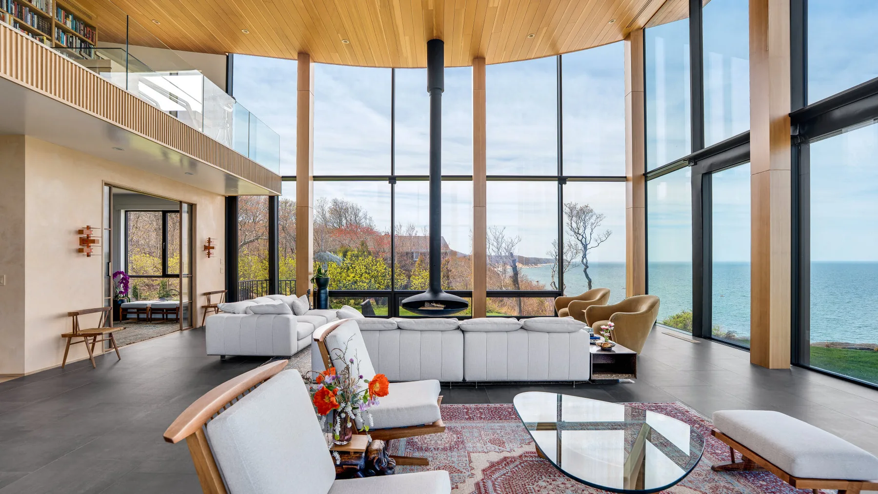 A bright living room with seating and large windows overlooking the water.