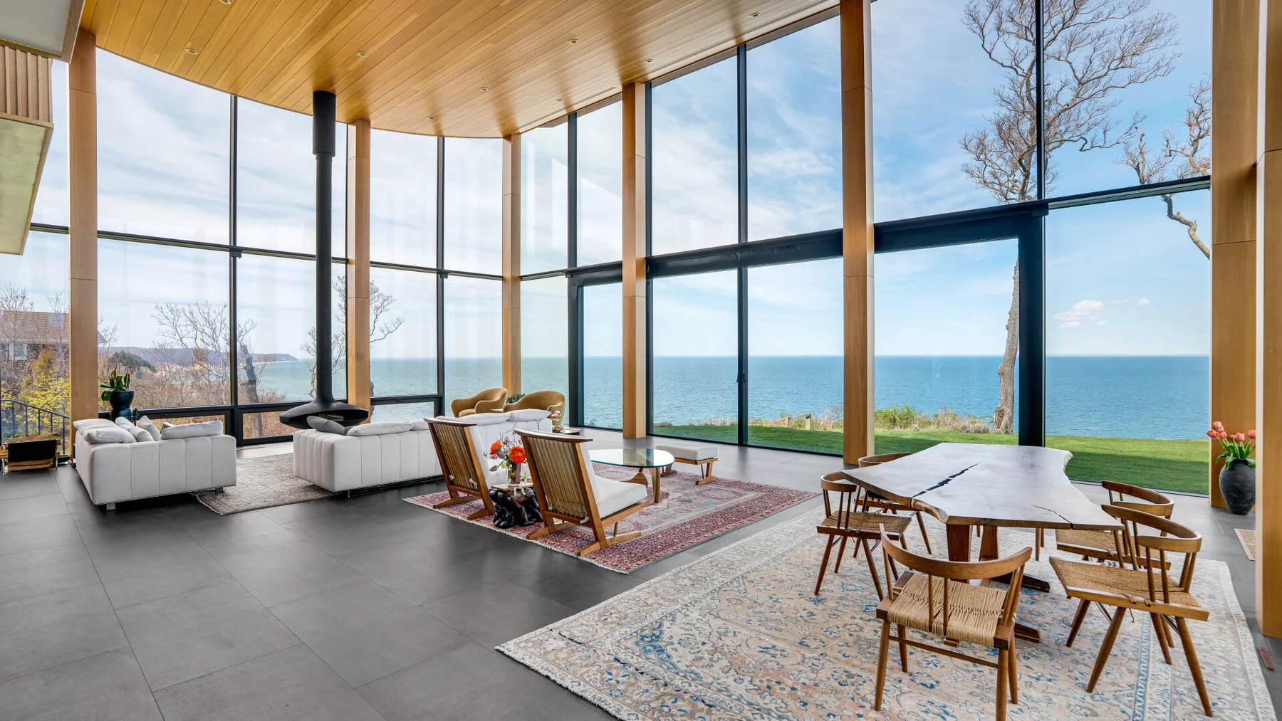 A bright living and dining area with floor-to-ceiling windows overlooking the water.