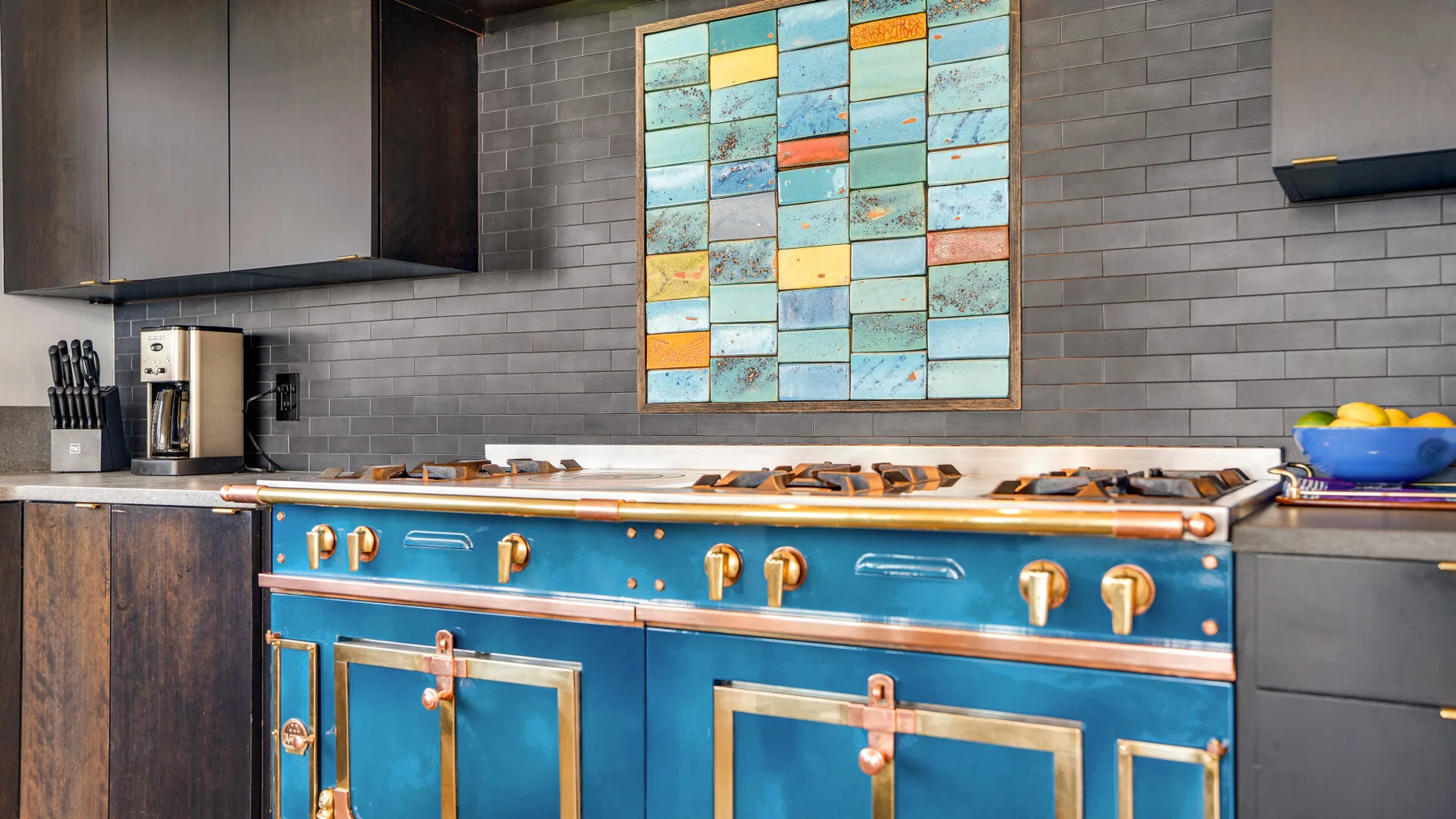 A kitchen with a blue range beneath colorful rectangular wall art.