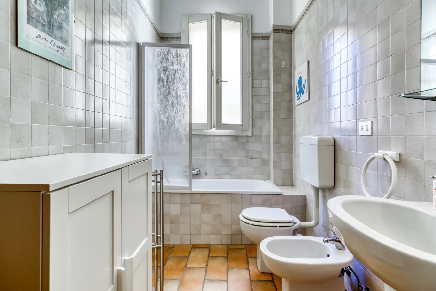 Un baño revestido de azulejos con bañera, inodoro y bidé.