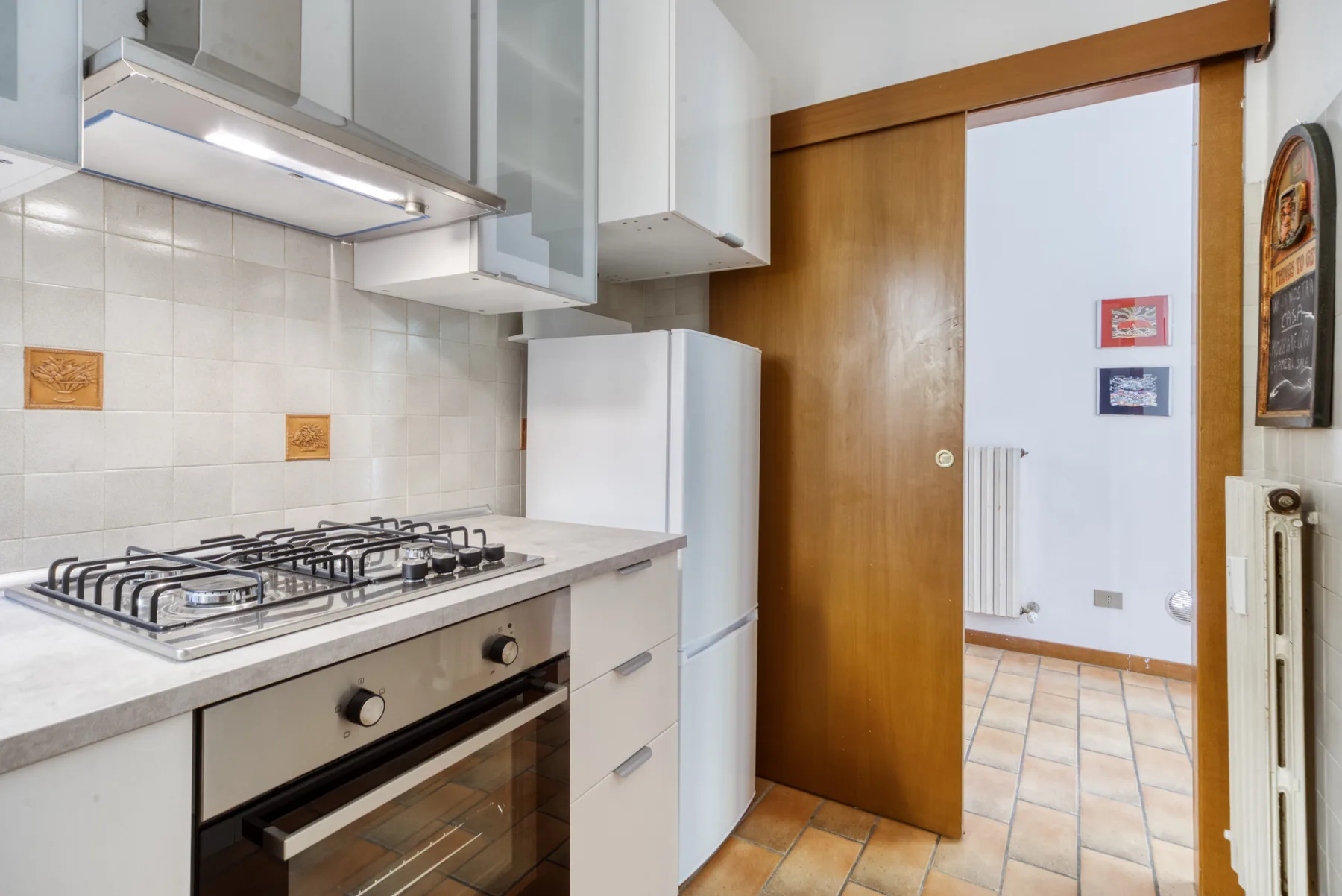 A compact kitchen with a stovetop and an open doorway to the next room.