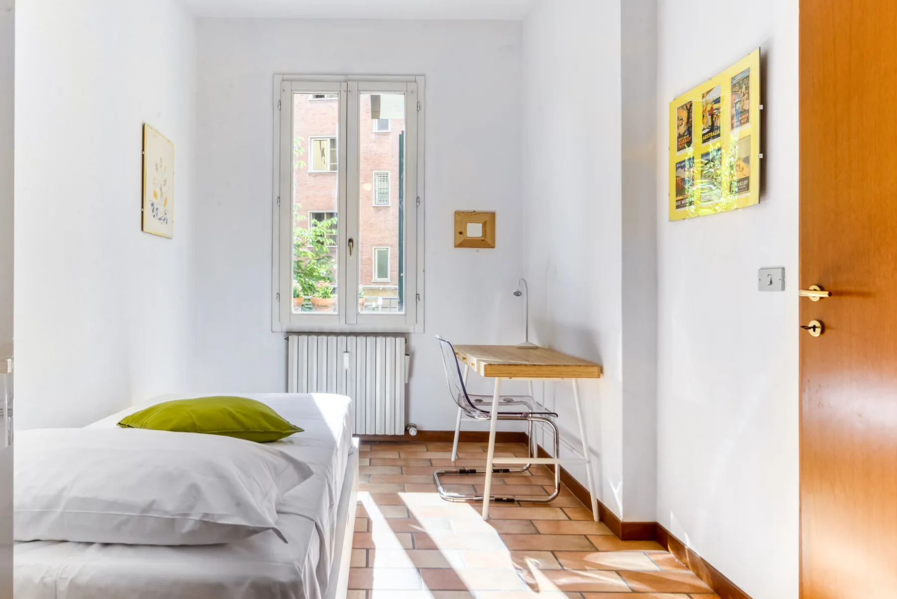 Un dormitorio luminoso con una cama, un escritorio y una ventana.