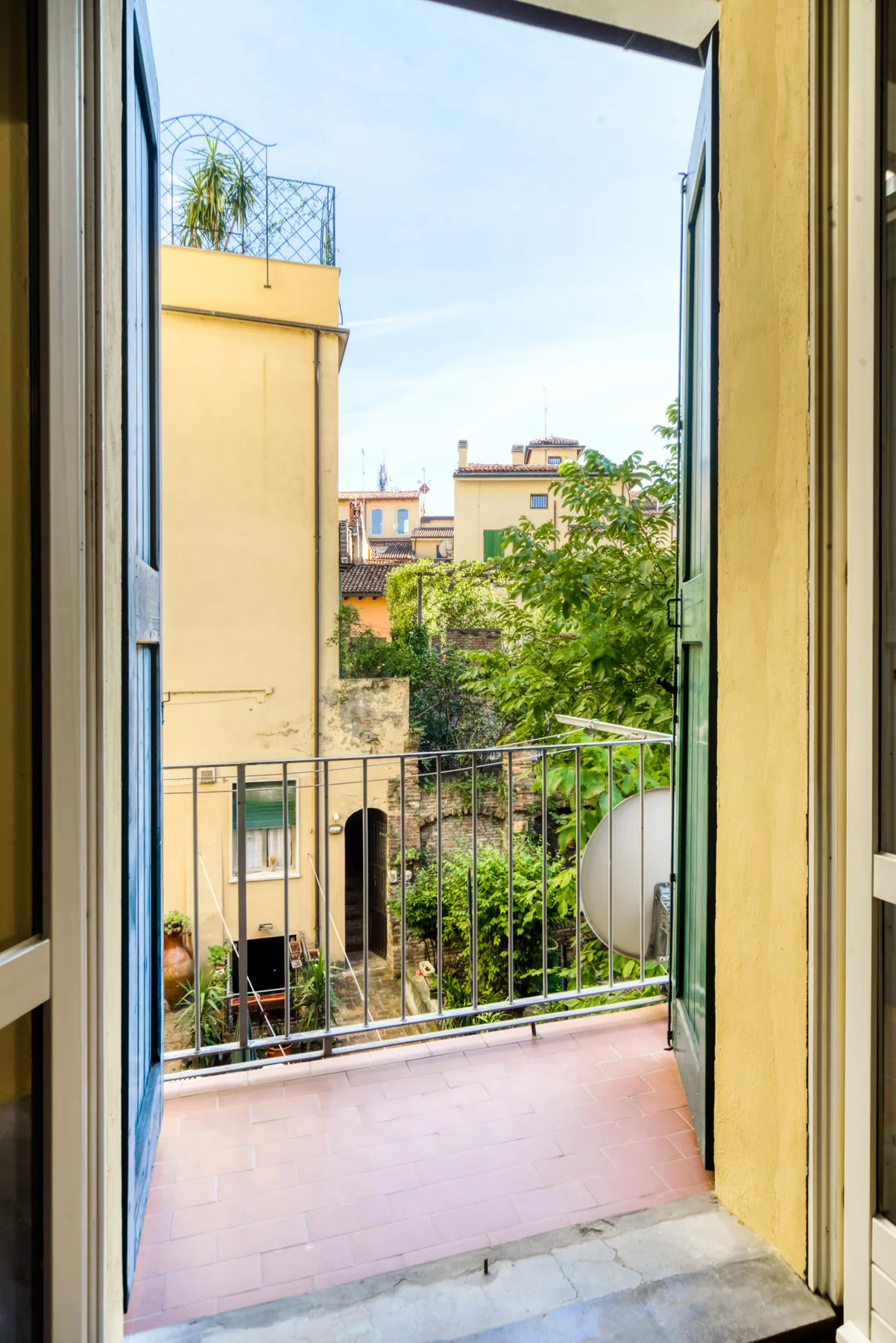 An open doorway leads to a small balcony overlooking nearby buildings and greenery.