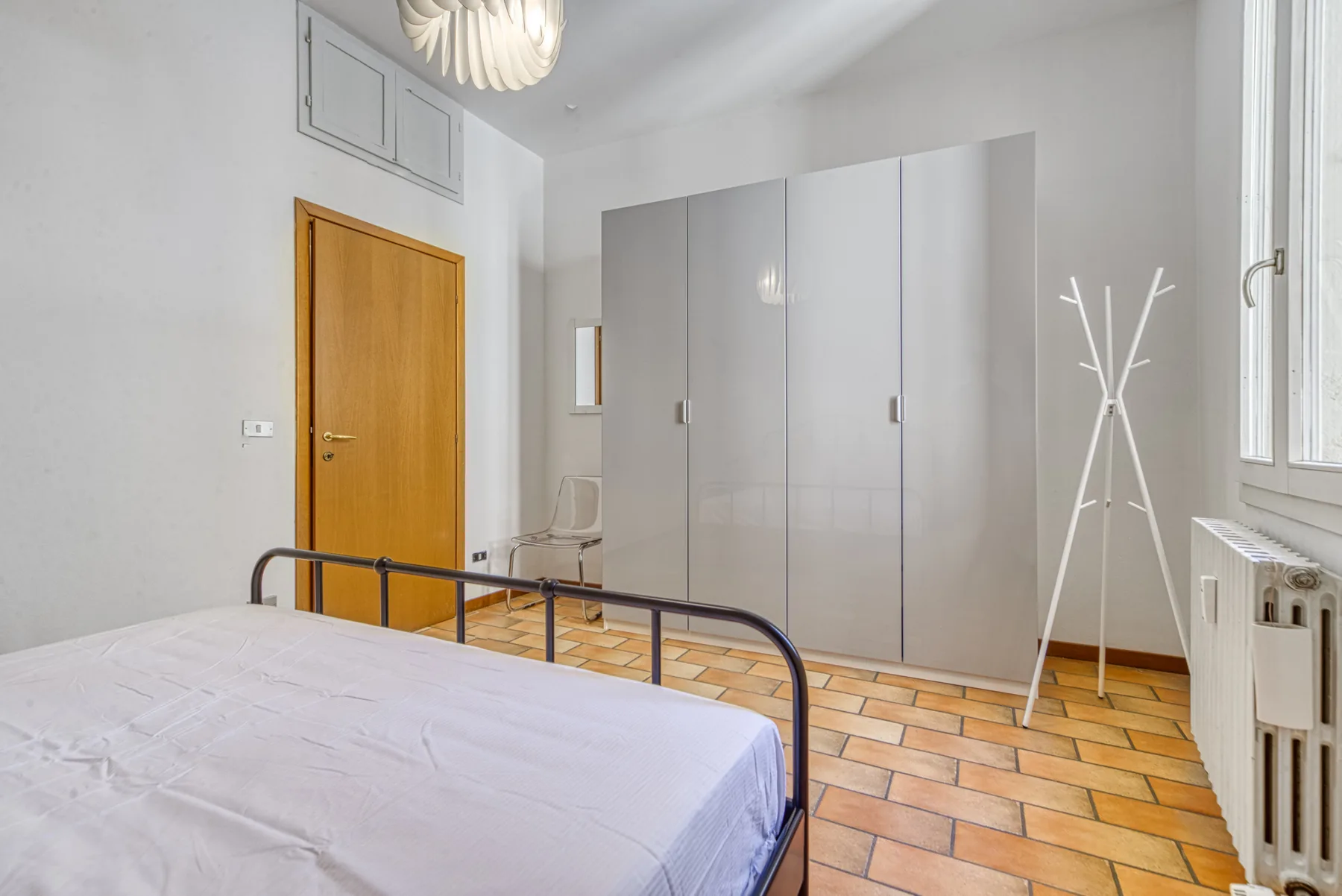 Un dormitorio con una cama, un armario y un perchero.
