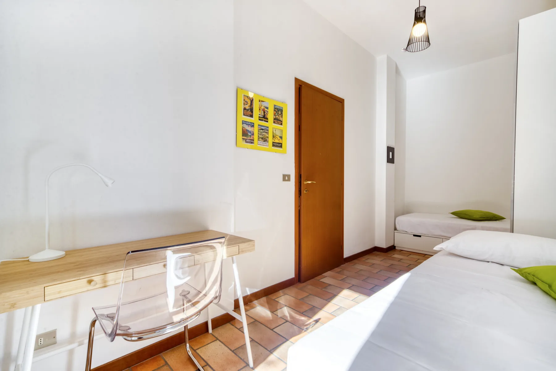 Un dormitorio luminoso con camas, un escritorio de madera y una silla.