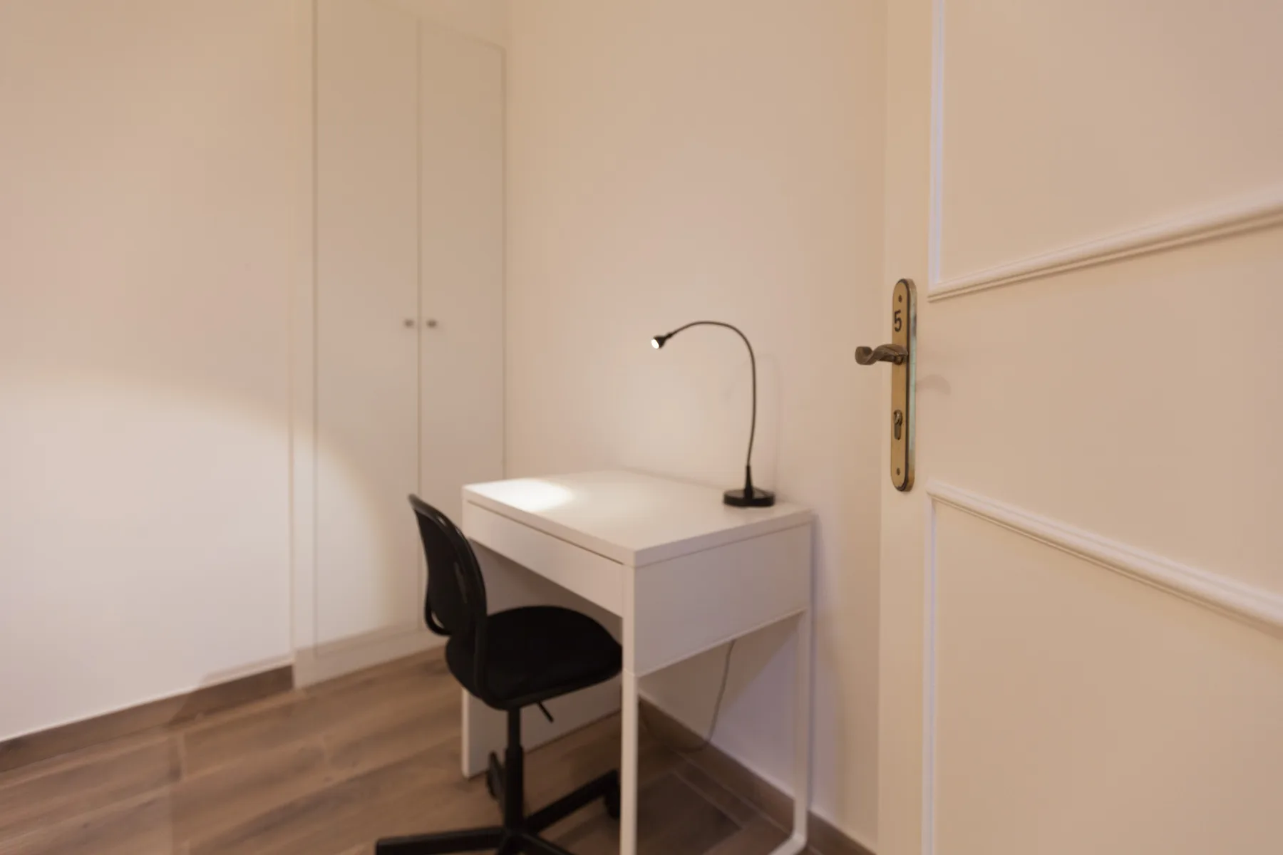 A small work area with a desk and chair sits beside a closed door.