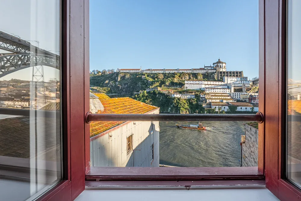 A river and hillside buildings are visible through an open window.
