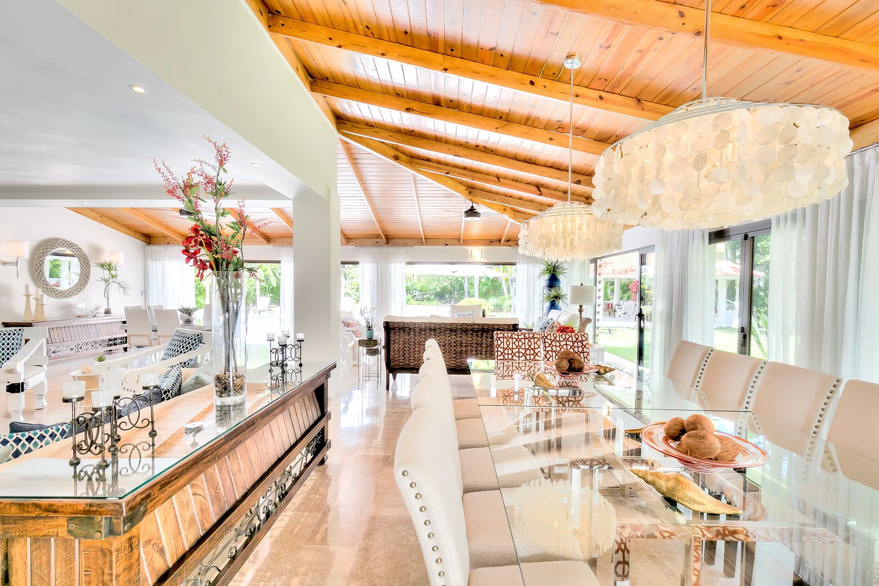 Un luminoso comedor con una larga mesa de cristal y una cocina abierta.