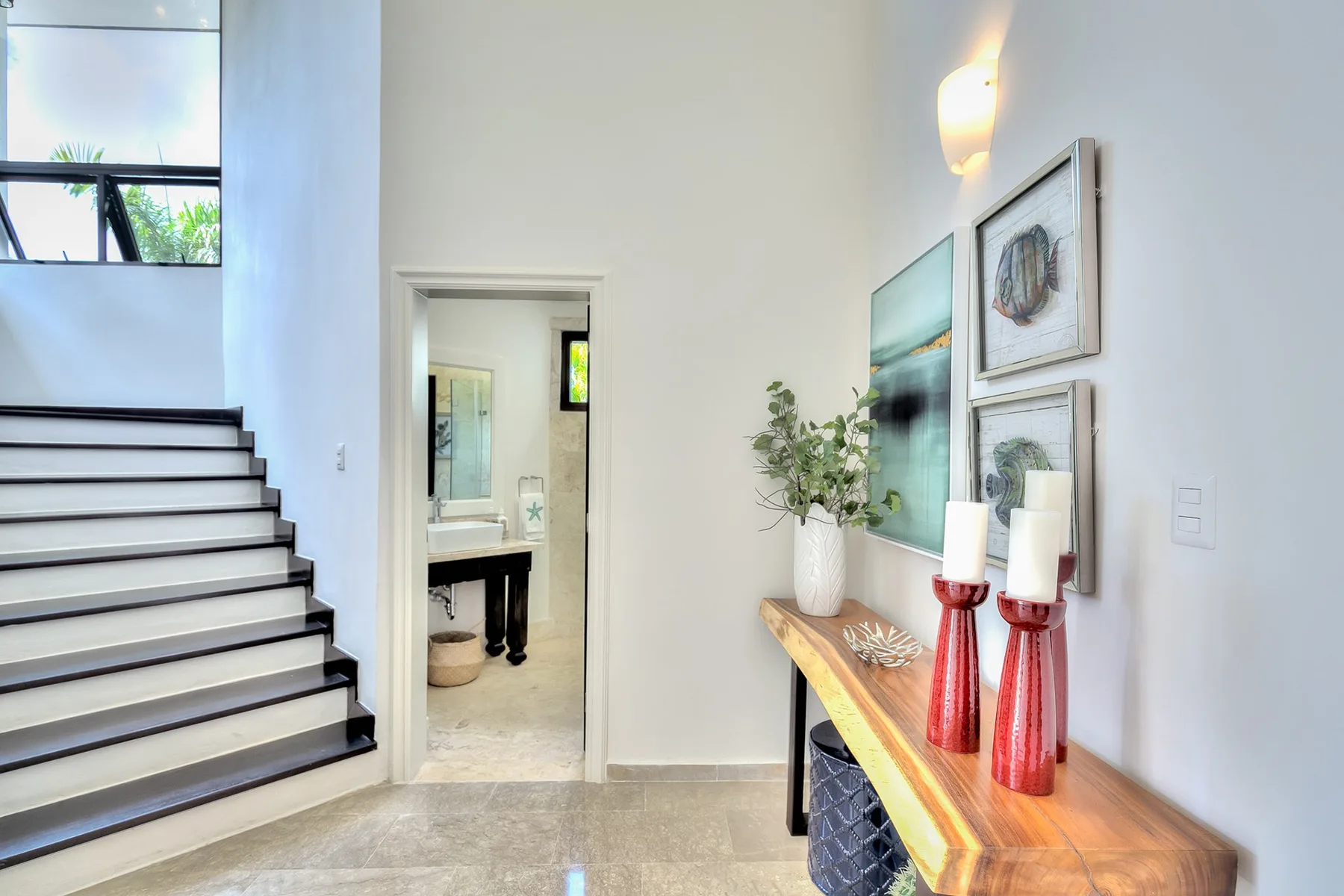 Un pasillo interior luminoso con una escalera y una consola de madera.