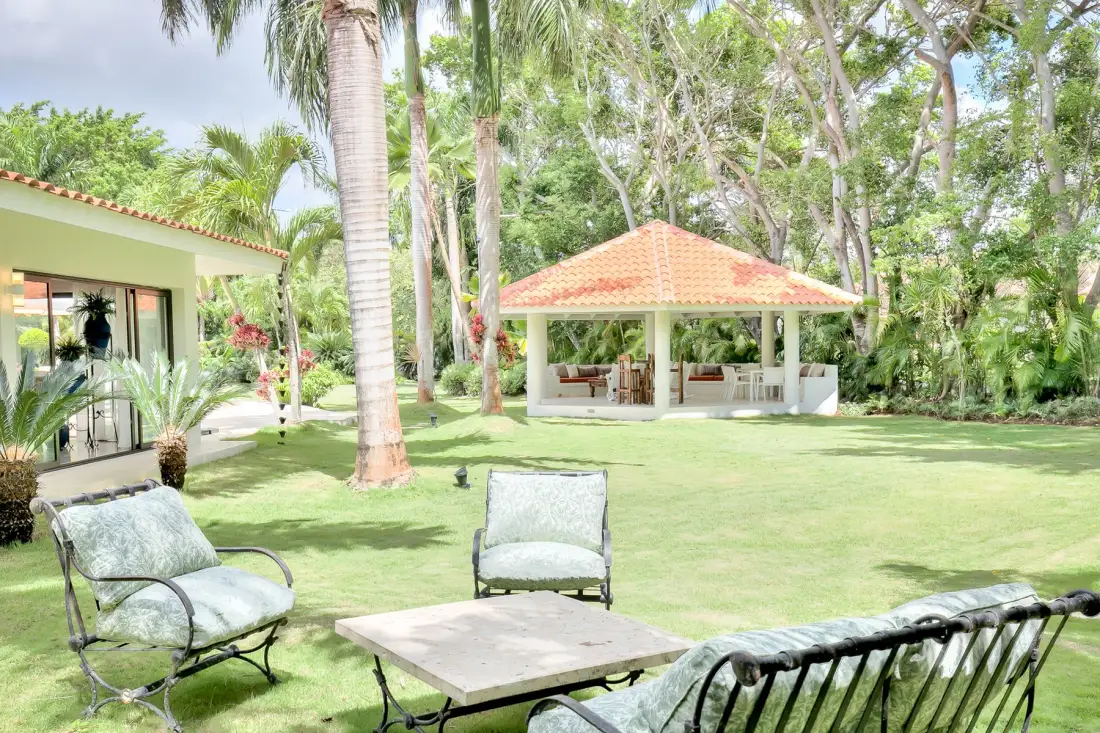 Un jardín ajardinado con asientos al aire libre y un pabellón cubierto entre palmeras.