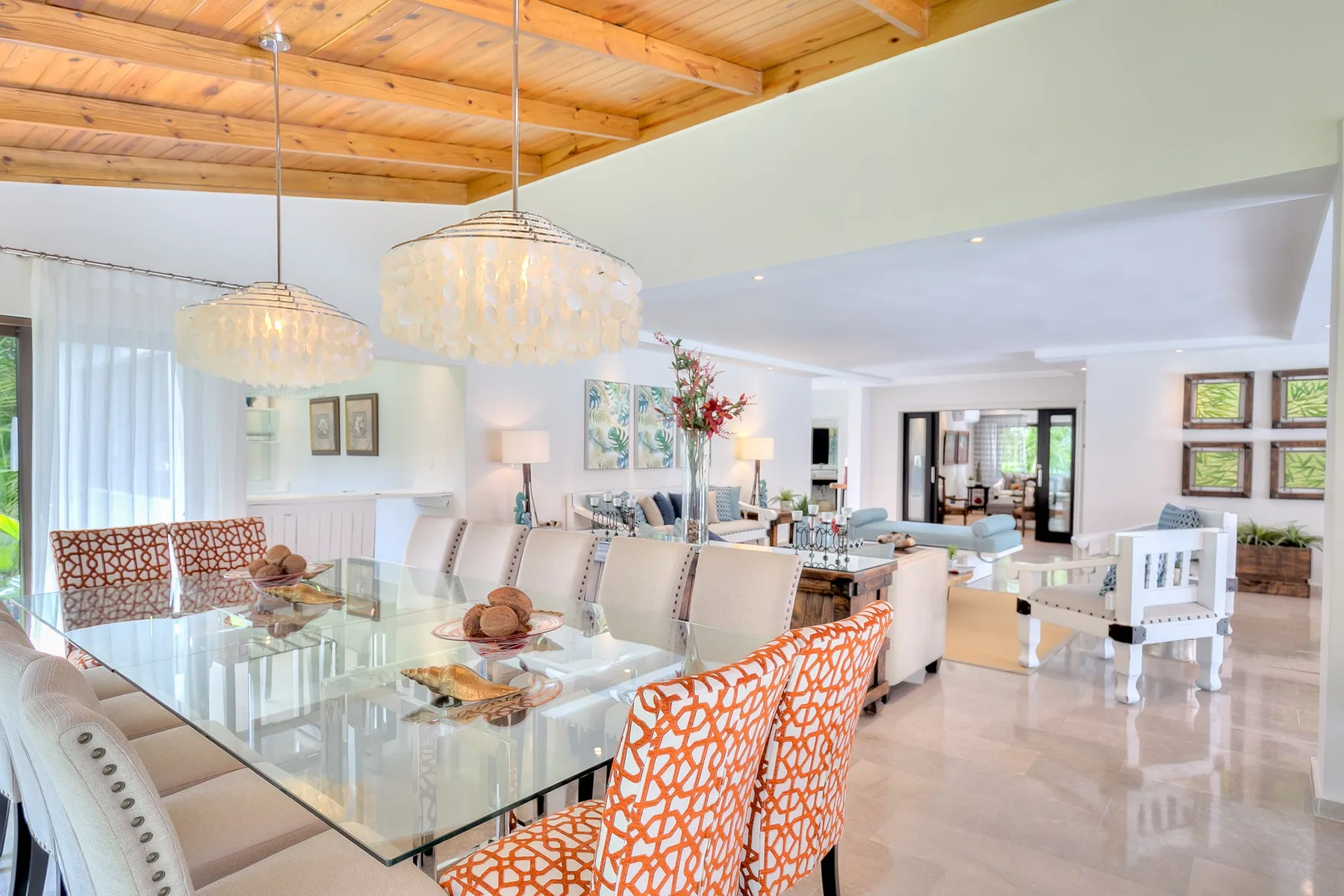 Una zona abierta de comedor y sala cuenta con una mesa de vidrio y asientos.