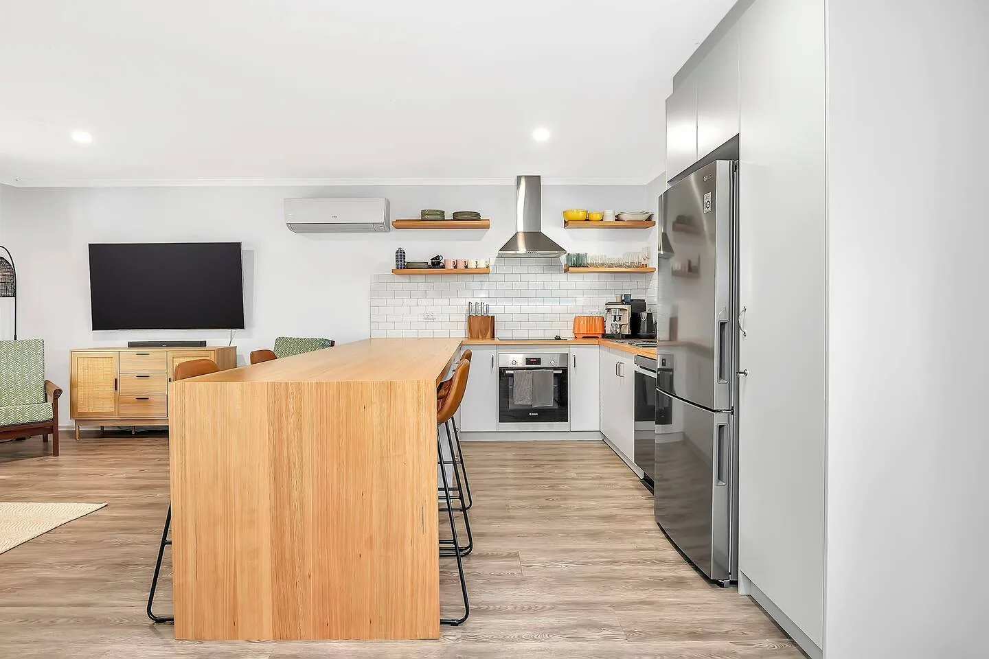 Cocina moderna con isla de madera, electrodomésticos de acero inoxidable y una zona de comedor contigua.