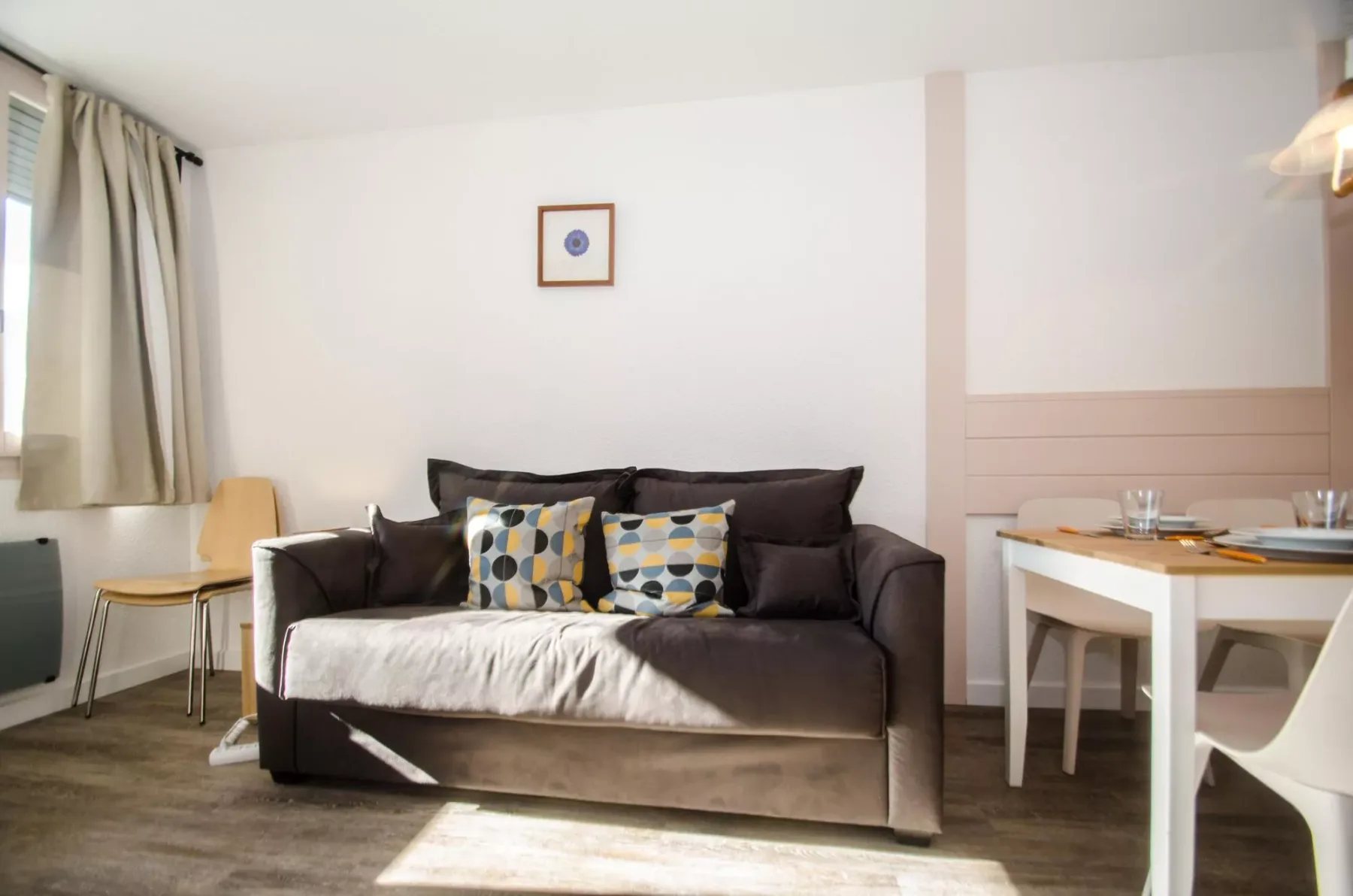 A living room with a dark sofa and a small dining table.