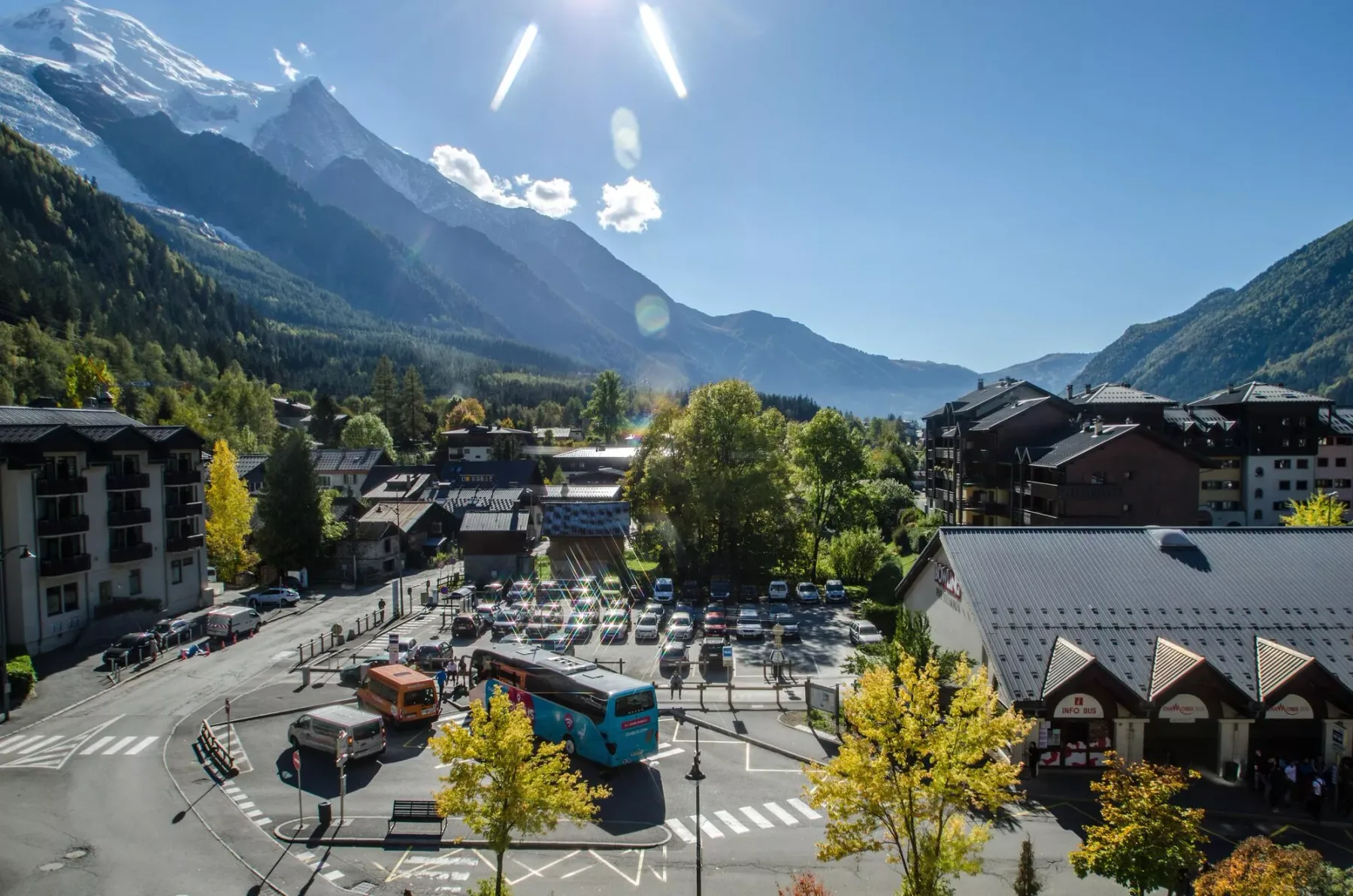A mountain town with buildings and a parking area beneath a clear blue sky.
