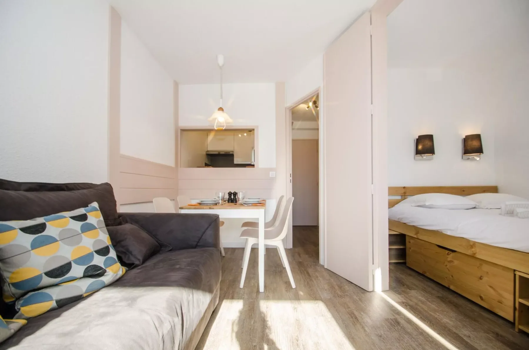 A compact room with a seating area, small dining table, and bed.