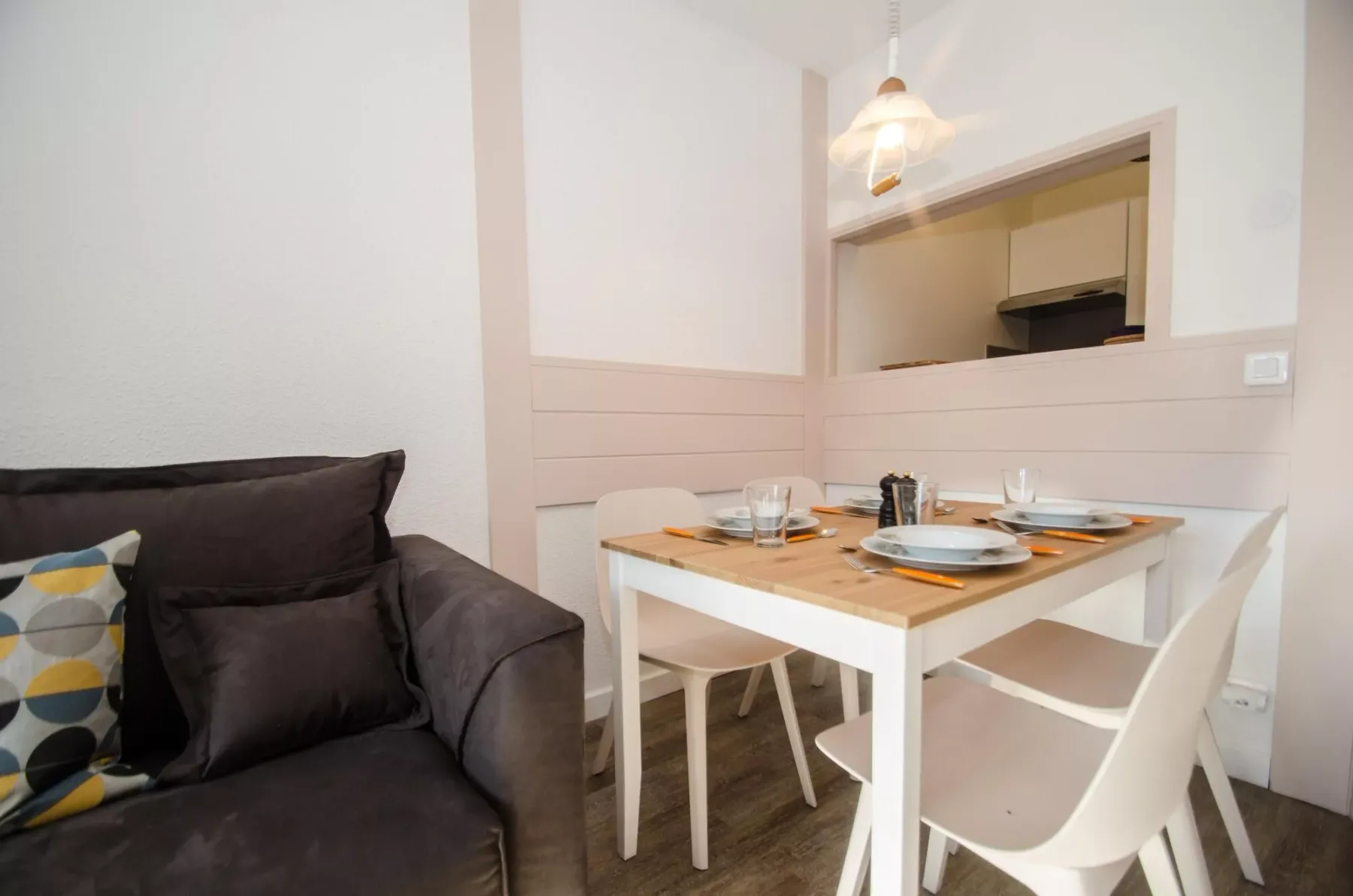 A dining area with a set table beside a dark sofa.
