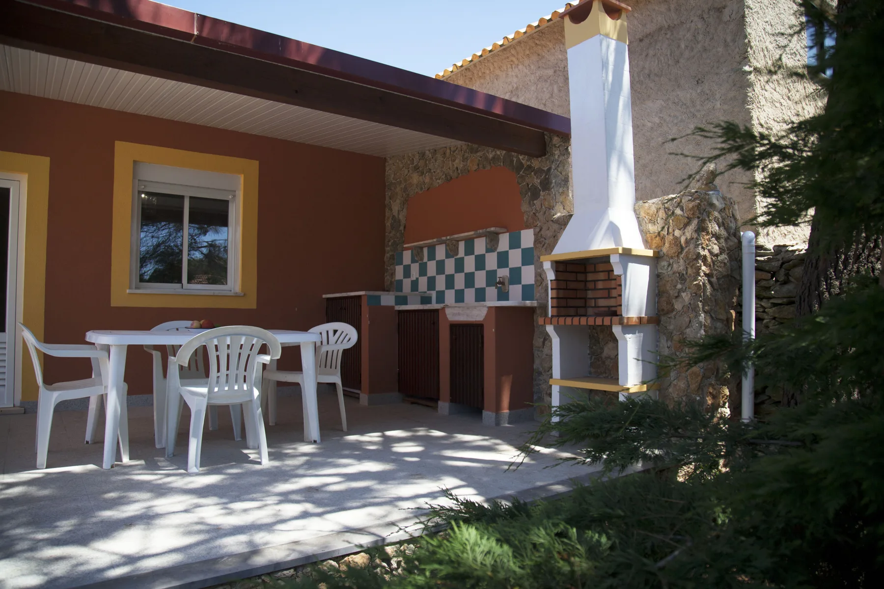 A patio with a dining table, seating, and a built-in barbecue.