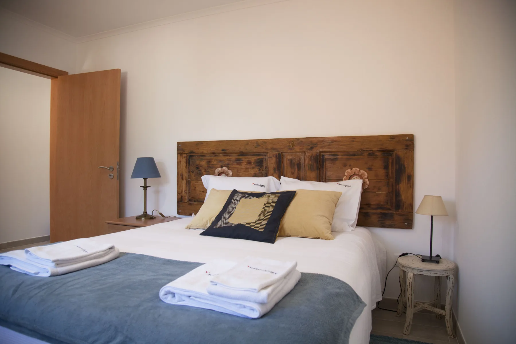 A bedroom with a double bed, wooden headboard, and folded towels.